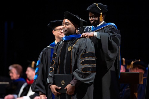 A graduate student receiving their master's hood at a Purdue commencement ceremony