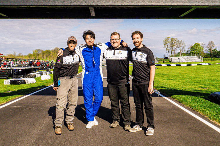 Four graduate students posing on the Purdue Grand Prix race track